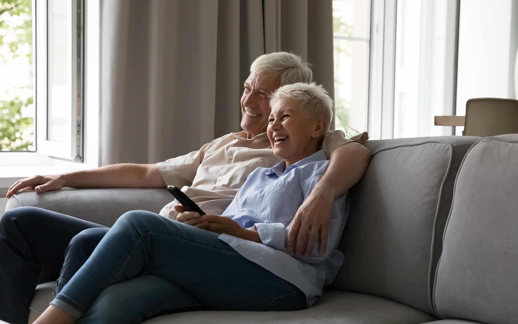 Senior couple sitting on couch enjoying television