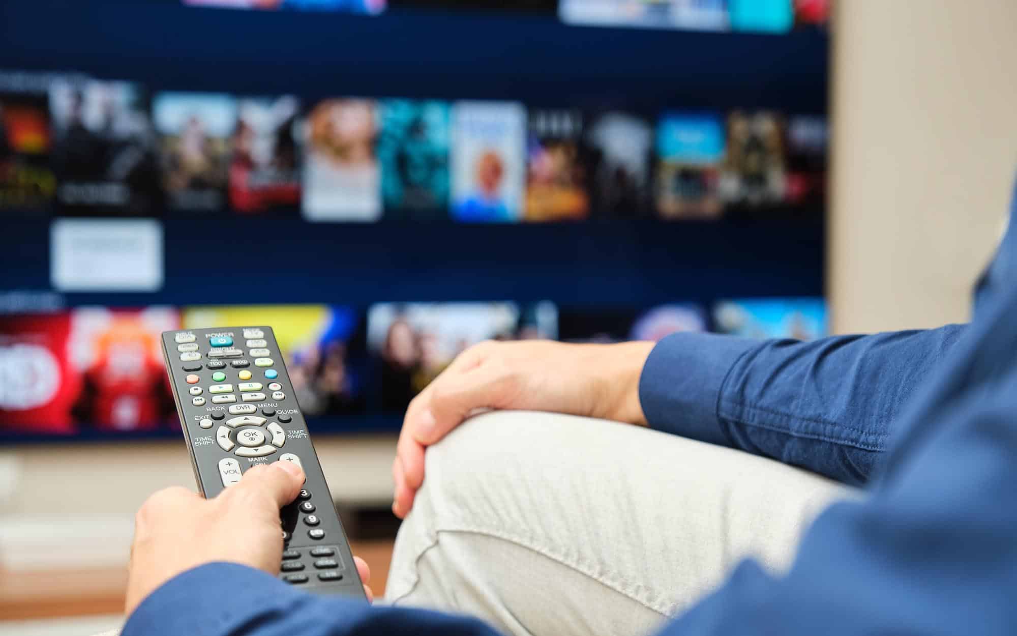 person at home using remote to look through tv